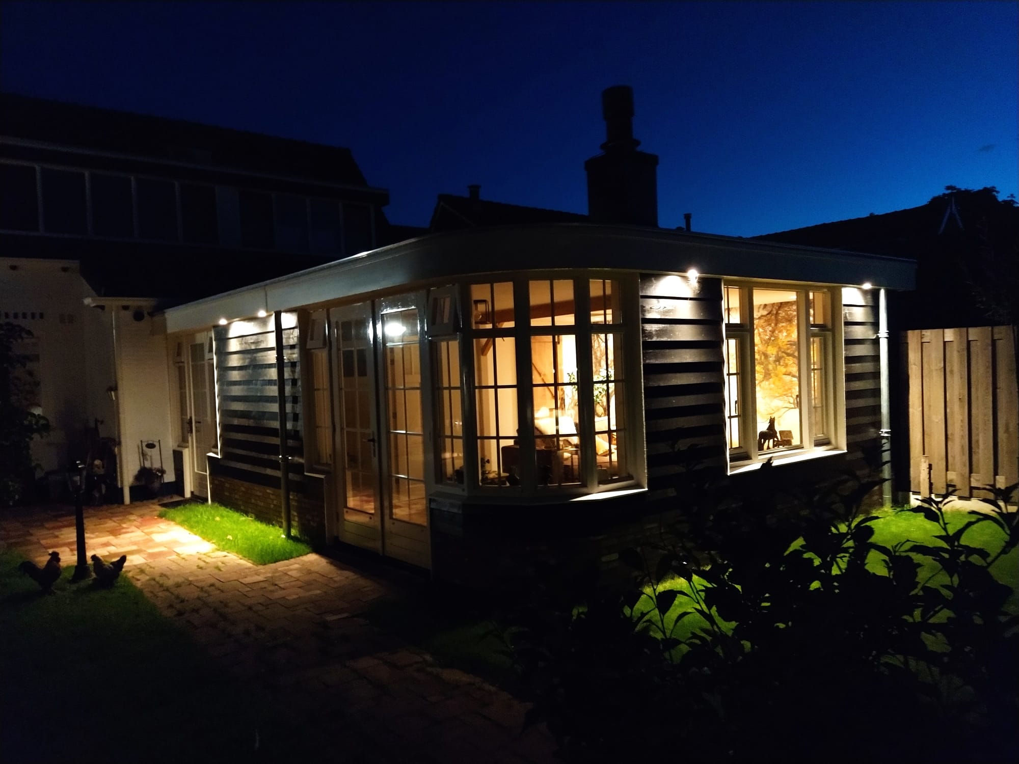Aanbouw met grote ramen en warme avondverlichting