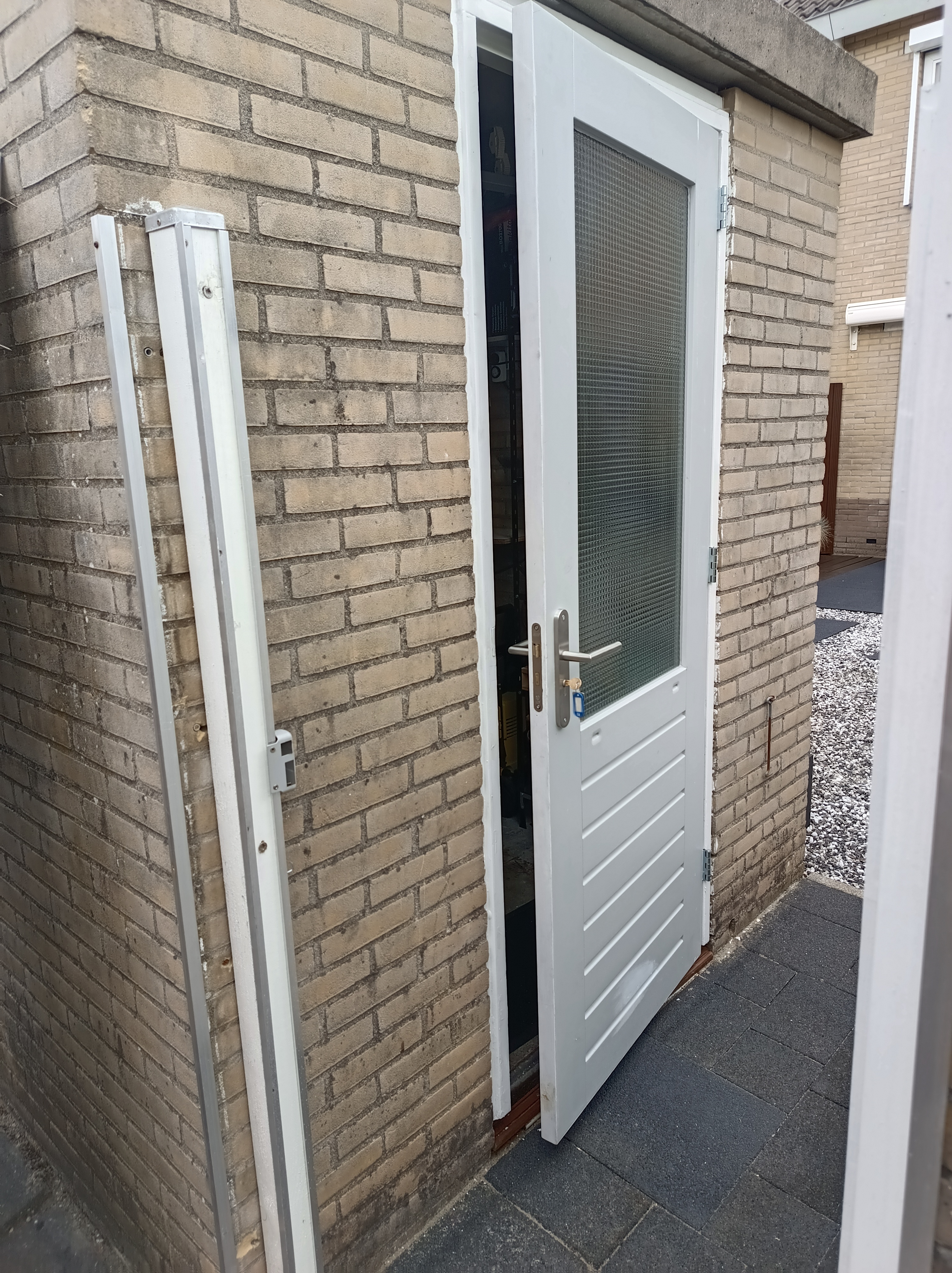 Witte buitendeur en kozijn in een bakstenen gevel